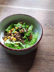 A delicious, fresh, juicy breakfast salad of lentils, corn and green lettuce is served in a ceramic plate. Dietary, healthy, vegetarian food made from ecological products.