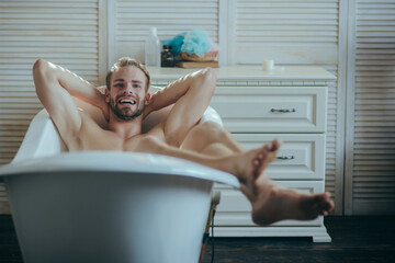 Man having joyful morning in bathtub. Smiling gay in bath tub.