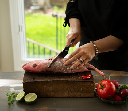 Woman cutting pink-orange snapper 