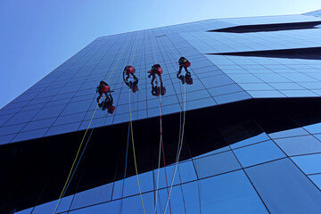Window cleaners abseiling down the exterior of an office building in Rome, Italy. - obrazy, fototapety, plakaty