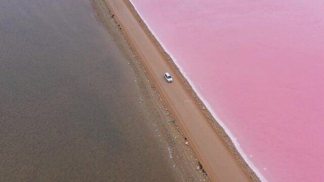 2020 - Excellent Aerial Shot Of Of A Car Driving Down A Road Dividing Lake MacDonnell On Eyre Peninsula, South Australia, With Brown Water On One Side And Pink On The Other.