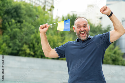 Happy middle aged men with Ukraine flag celebrating Independence Day. Sports fan for national team Ukraine.