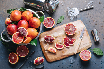 Summer cocktails and fresh orange juice cooking concept. Whole and sliced blood oranges with shaker...
