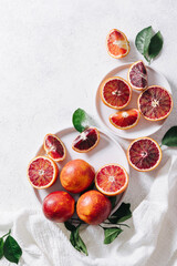 Composition of whole and sliced blood oranges in a plate on white table background. Flat lay, top...