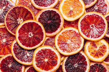 Bright colorful background of fresh ripe sliced blood oranges. Close up, flat lay. Orange texure,...