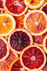 Bright colorful background of fresh ripe sliced blood oranges. Close up, flat lay, top view. Orange...