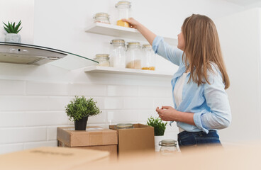 Woman arranges kitchen utensils after moving to new apartment.