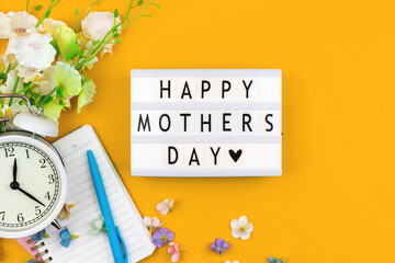 Fototapeta na wymiar Happy Mothers Day flat lay card concept, yellow background with spring decorative flowers, top view, text message