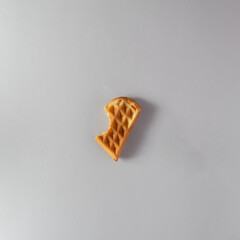 Bitten waffle on a gray background. Flat lay, top view, copy space