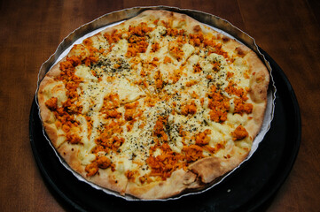 chicken pizza with cheese in a form on top of a wooden table