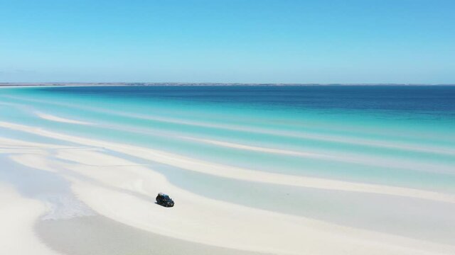 2020 - Excellent aerial shot of a van parked on the white sands near the clear blue water of Flaherty Beach on Yorke Peninsula, Australia.