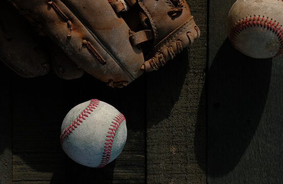Used baseballs and glove from top view on dark wood background as sports graphic image with copy space.