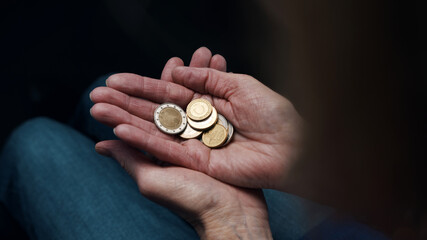 Old woman counting coins in her wrinkled hands. Close up. High quality photo