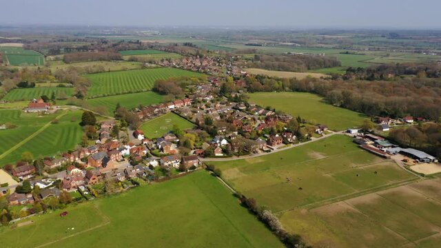 4K aerial drone footage of rural village amongst rolling farm fields the in countryside of Berkshire, UK