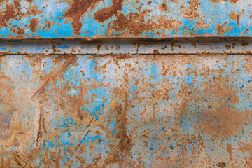 Rusty old part of a steel car door with rusty streaks and stains. Destruction of layer of paint. 