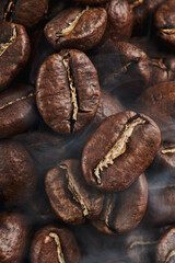 Close macro view of Viennese dark medium roasting process coffee beans with smoke with the second crack. Rich coffee taste and full body. Brown color