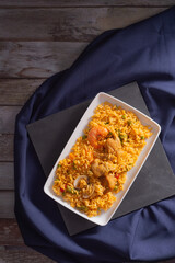 Mexican style chicken paella with seafood on wooden background