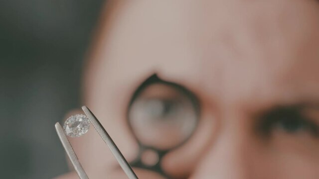 A goldsmith in jewelry checks the quality of luxury brilliant diamonds. The diamonds of high caliber shine the light and pure. Concept: Jewelry, luxury, glitz, gloss and goldsmith.
