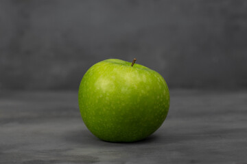 Single green apple on grey concrete background. Healthy life concept.
