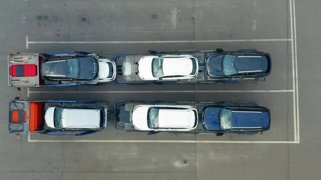 Aerial top down view of a car transporter loaded with cars on a parking lot