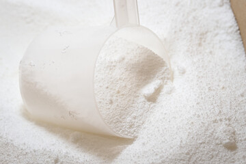 A scoop measures out laundry detergent powder for washing machine use.