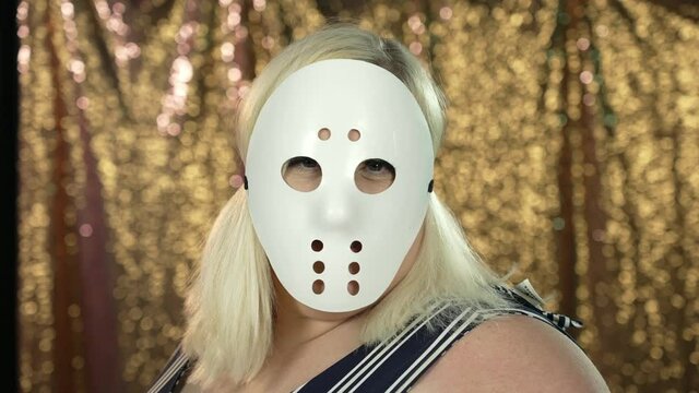 A slow motion view of a woman in a white hockey face mask dramatically turning to camera. Shot at 120fps  	