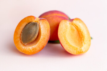Ripe red homemade apricots with leaves on a pink background