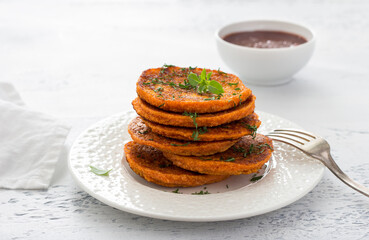 Lentil fritters with plum sauce, tkemali, greens in a white plate on a light blue textured background. Healthy vegan food