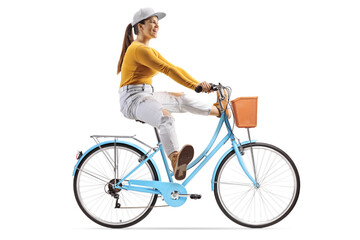 Full length profile shot of a young female riding a bicycle and lifitng legs