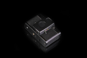 The old very popular automatic film camera on black glass background with reflection.