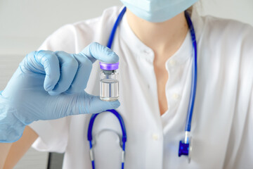 Coronavirus vaccine flask in hand of pharmaceutical bio research scientist. Vaccine development and testing laboratory, selective focused. Close up