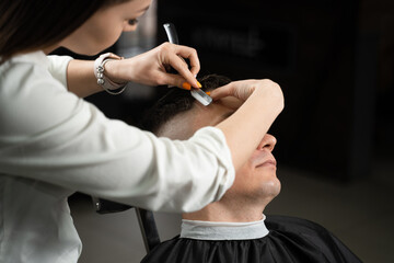Straight razor cut man hair in barbershop. Attractive woman barber making hairstyle for handsome...
