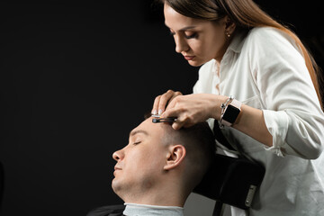 Straight razor cut man hair in barbershop. Attractive woman barber making hairstyle for handsome man.