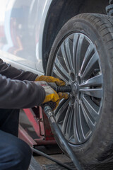 Removing car mechanic to repair the leaky tire car wheels.Mechanic changing a car tire on a vehicle a hoist using an electric drill to loosen the bolts .concept of service or replacement.