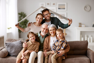 Big happy family sitting on the coach under paper roof and smiling at camera