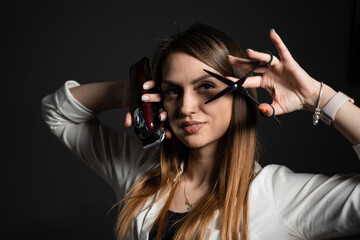 Woman barber with scissors and hair clipper in barbershop. Portrait of hairdresser for advert.