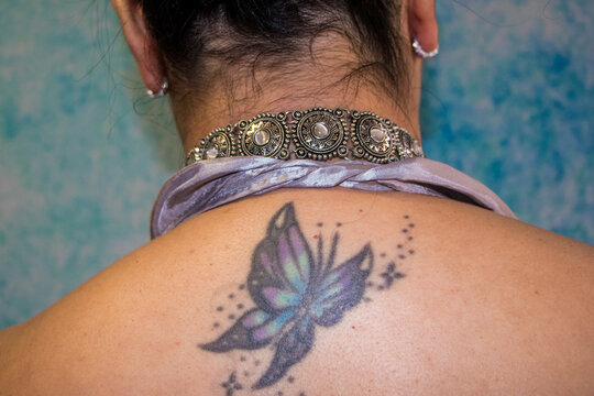 Jovem mulher de costas mostrando tatuagem de borboleta azul