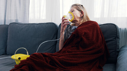 Elderly woman using oxygen mask at her home. High quality photo