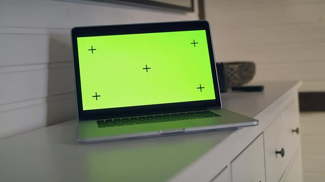 View of a table with a laptop computer with a green screen. 