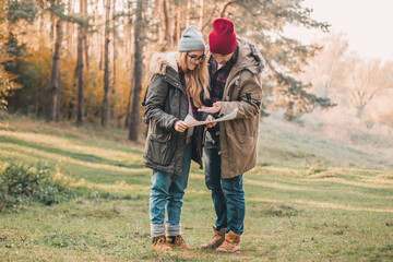 Traveler couple with map, compass and backpack exploring forest. Freedom and active travel concept.