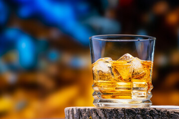 Glass of whiskey or cognac and ice cubes. Scotch whiskey, a whiskey glass filled with natural ice cubes, stands on an oak whiskey stand against the backdrop of the city at night.