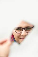 Naklejka premium Frau mit roten Haaren spiegelt sich in einer Spiegelscherbe, Nahaufnahme