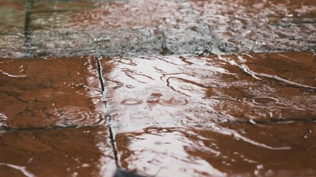 Heavy Rain Falling On Red Pavement. Low Angle, Close Up, Locked Off