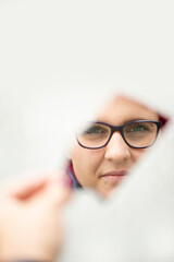 Naklejka premium Frau mit roten Haaren spiegelt sich in einer Spiegelscherbe, Nahaufnahme