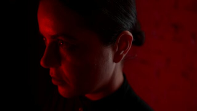 scared woman in dark room with scary red light, looking back, waiting demon or devil