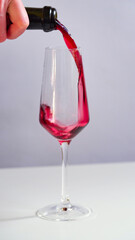 Close-up of a sommelier, a waiter pours red wine, juice or champagne into a glass glass. Alcohol in a glass.