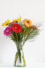 Vaso de vidro transparente com flores coloridas.