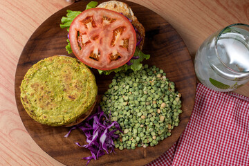 Homemade vegan and vegetarian hamburgers of legumes and vegetables with potatoes lettuce tomato on wooden plate for a healthy diet and life