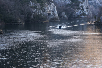 Boat goes by the river in Matka Canyon in Skopje, Macedonia. Matka is one of the most popular outdoor destinations in Macedonia. - obrazy, fototapety, plakaty