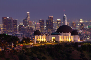 Griffith Observatory at night with the Los Angeles skyline in the background. 